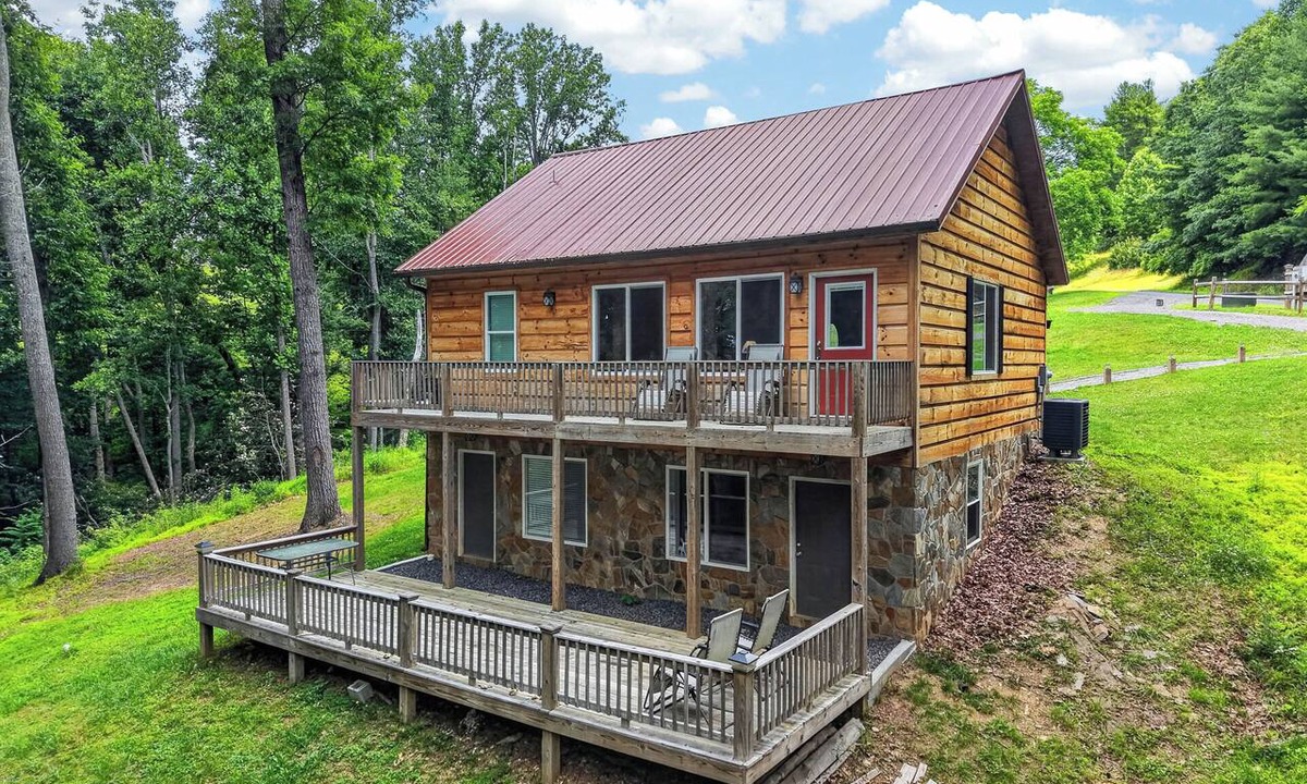 Galax House | A secluded, multi-level log cabin featuring a spacious wooden deck, open-concept living, a fully equipped modern kitchen, and comfortable sports-themed bunk rooms.